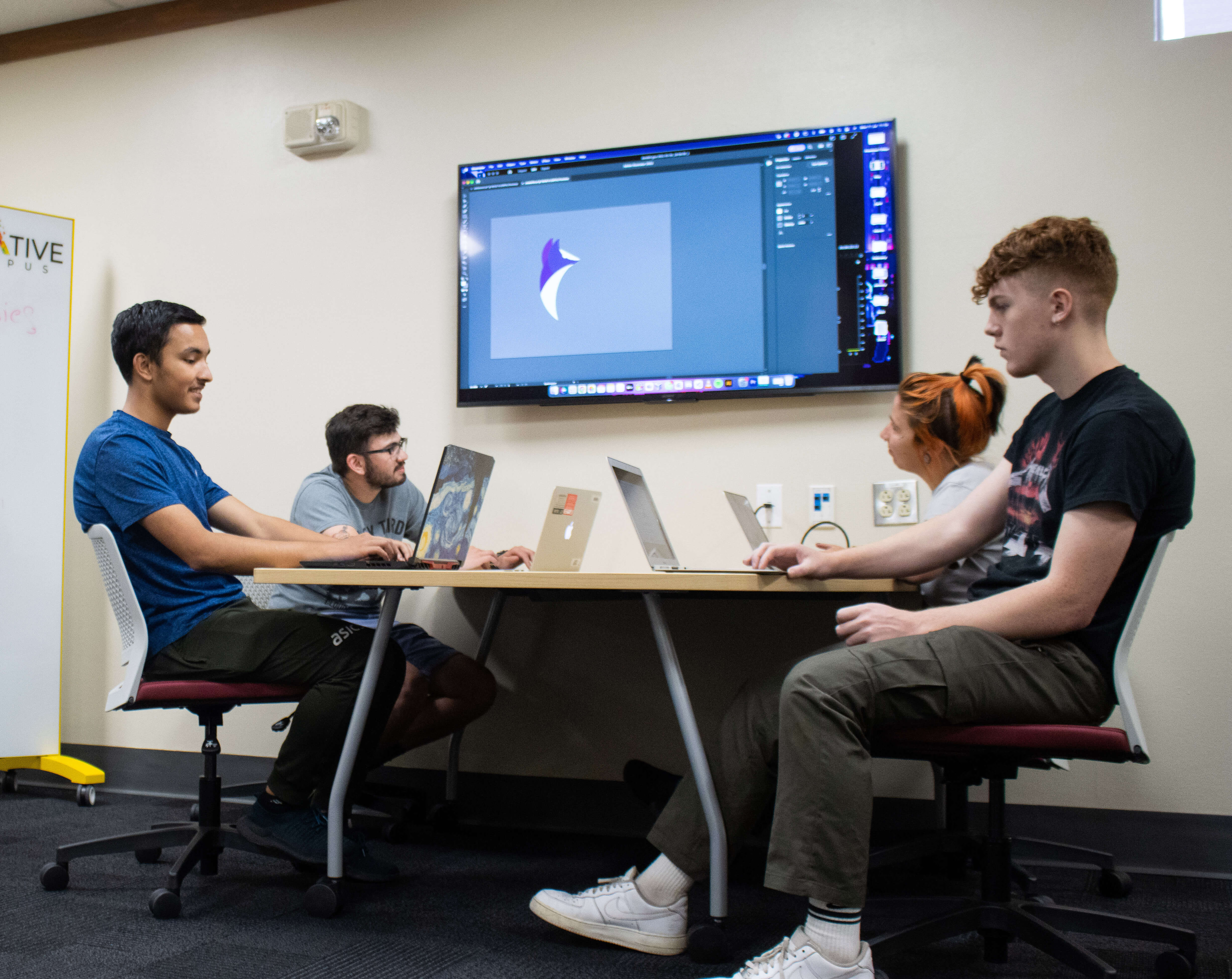 Students gathered around a screen using adobe creative cloud